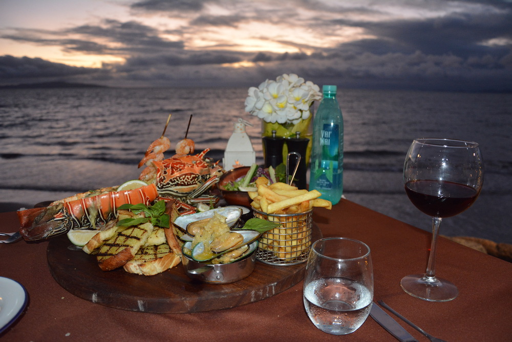 Seafood banquet served by the beach with a glass of red wine
