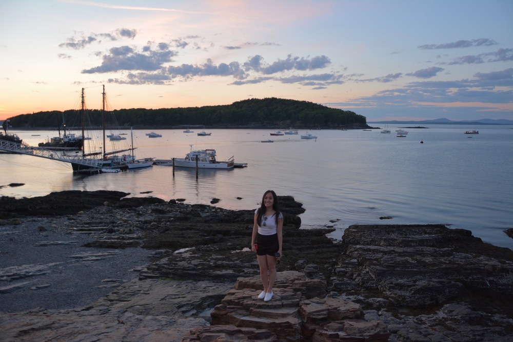 Frances standing on the stones along the Bar Harbor coast