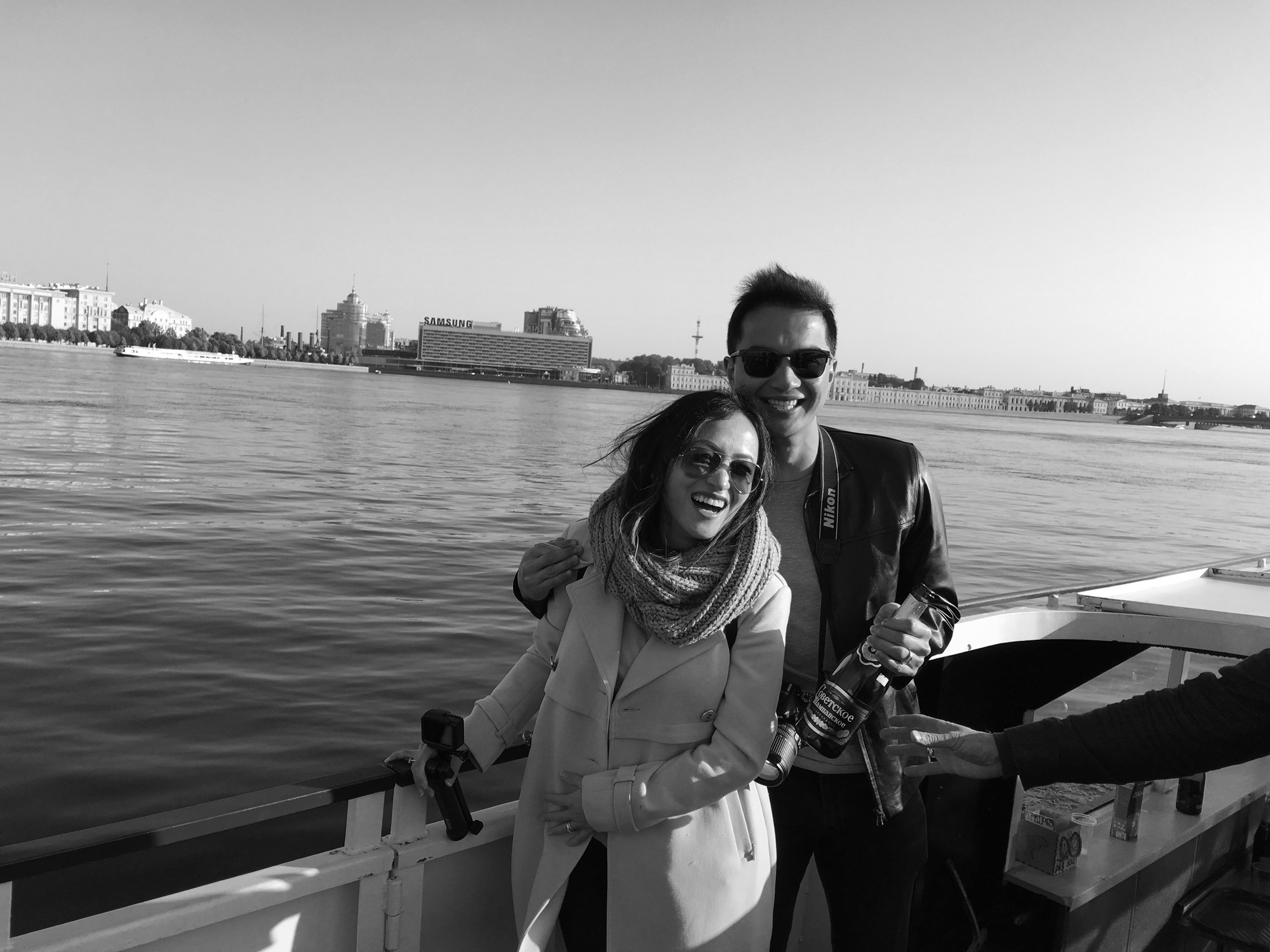 A couple laughing aboard a ferry with a backdrop of Saint Petersburg palaces